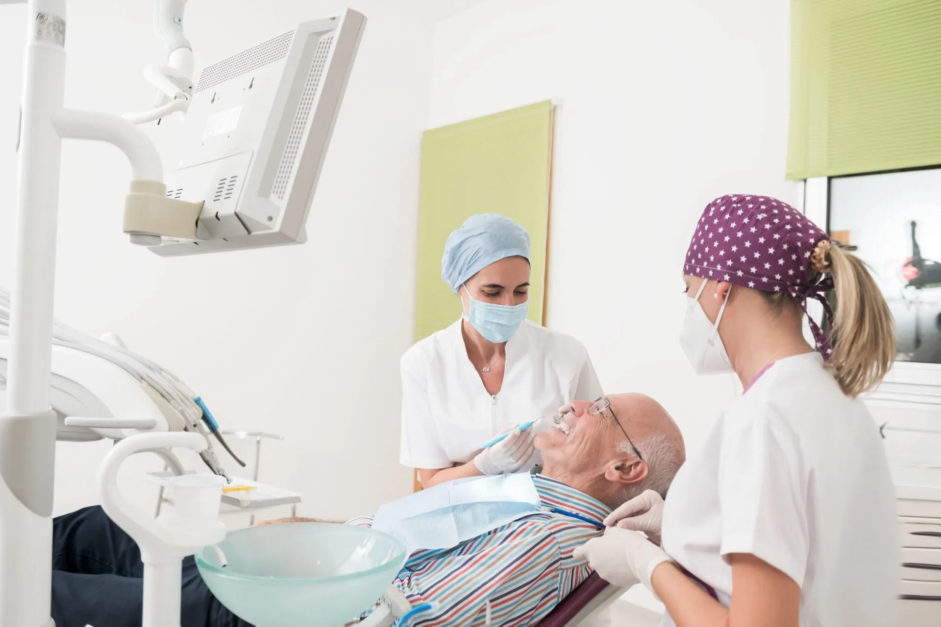 Dos profesionales de Enamel Clínica Dental atendiendo a un paciente adulto en el gabinete