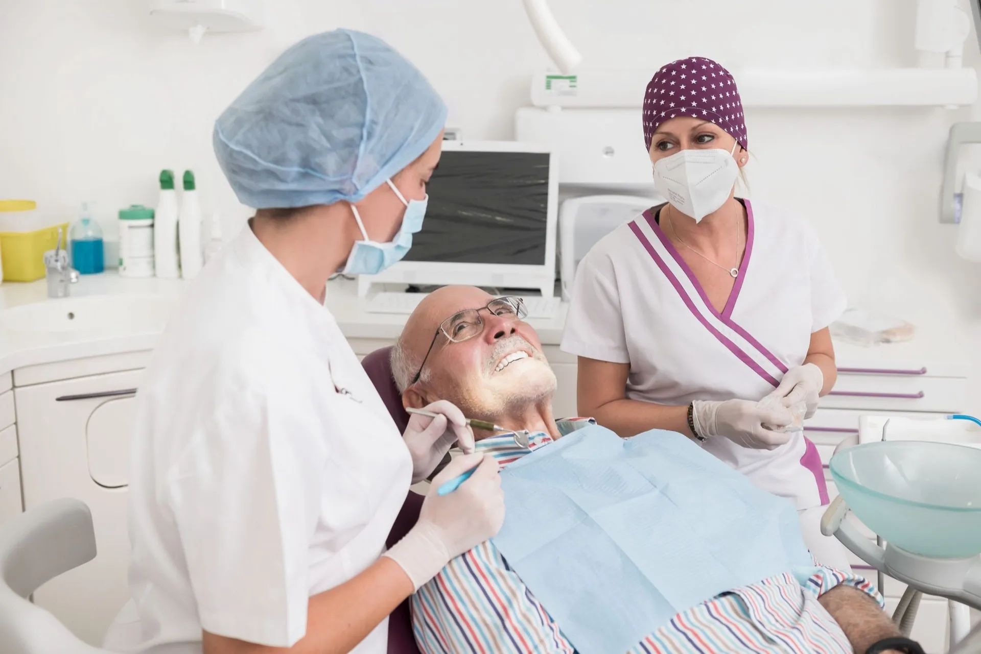 Paciente sonriendo en el sillón de Enamel Clínica Dental mientras le atienden dos profesionales